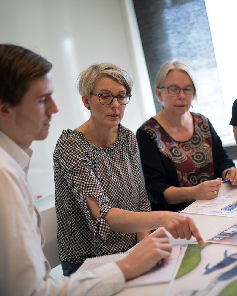 A group of HAGS employees sit around a desk discussing playground design schemes.